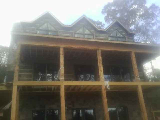 Dormers and porch framing on a large log home under construction — Roof Coating work by our crew in Solana Beach