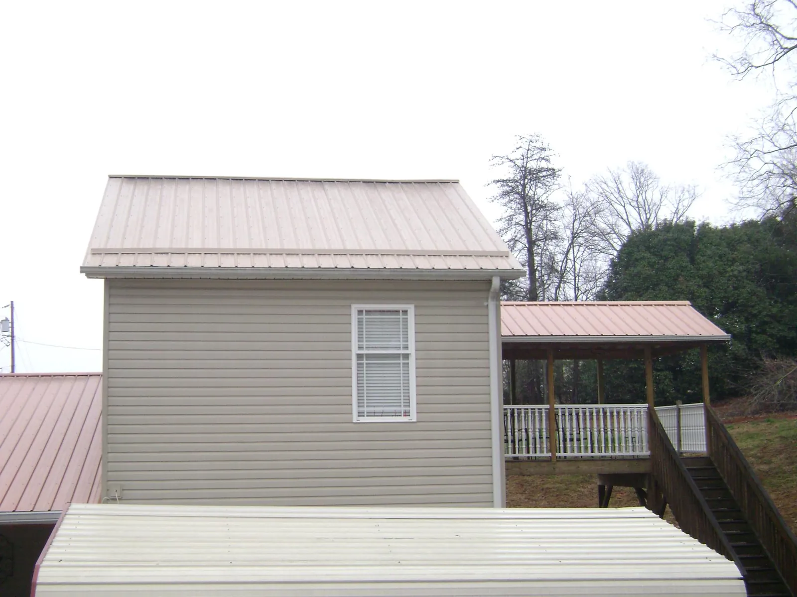 Tan metal roofs on a two story addition and attached porch, from a Roof Replacement job in Solana Beach