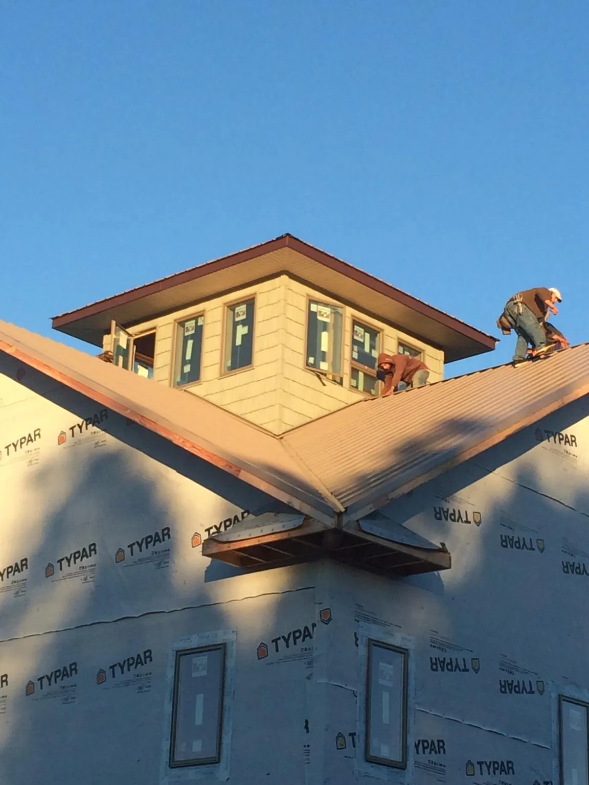 Roofers working around a rooftop cupola on a new metal roof at sunset — Roof Waterproofing in Solana Beach by Roofing Brothers